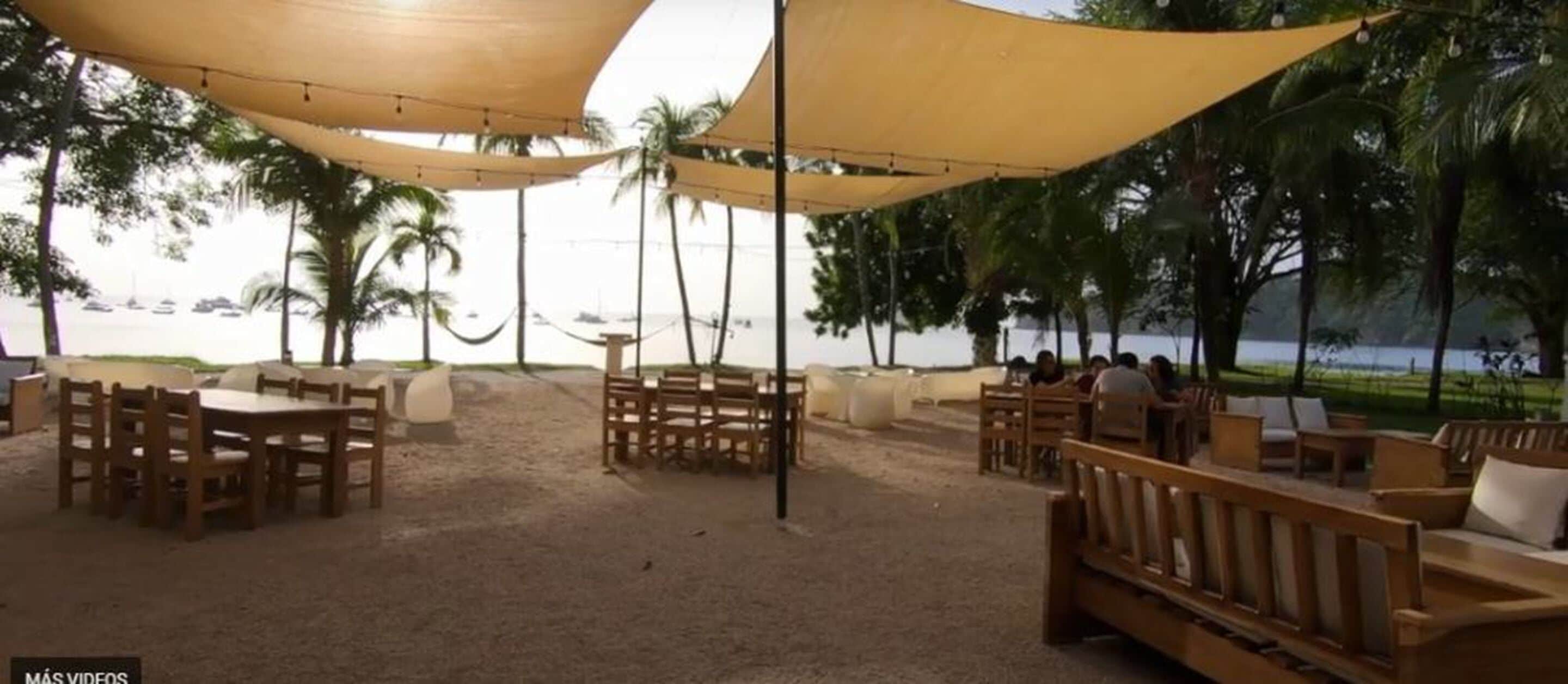 An outdoor seating area with wooden furniture and a view of the beach and ocean.