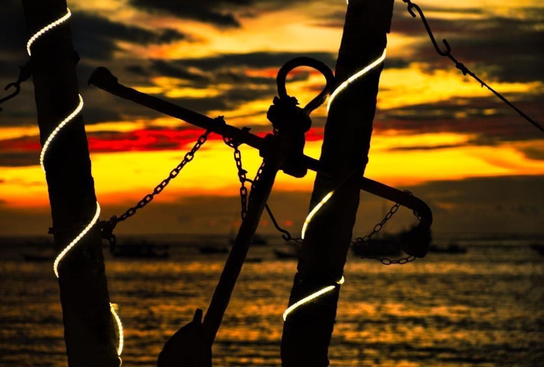 Un atardecer con cadenas y grilletes silueteados contra el cielo.