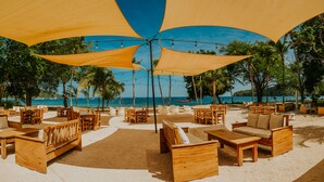 Un salon de plage doté de mobilier en bois et de grands parasols offrant de l’ombre.