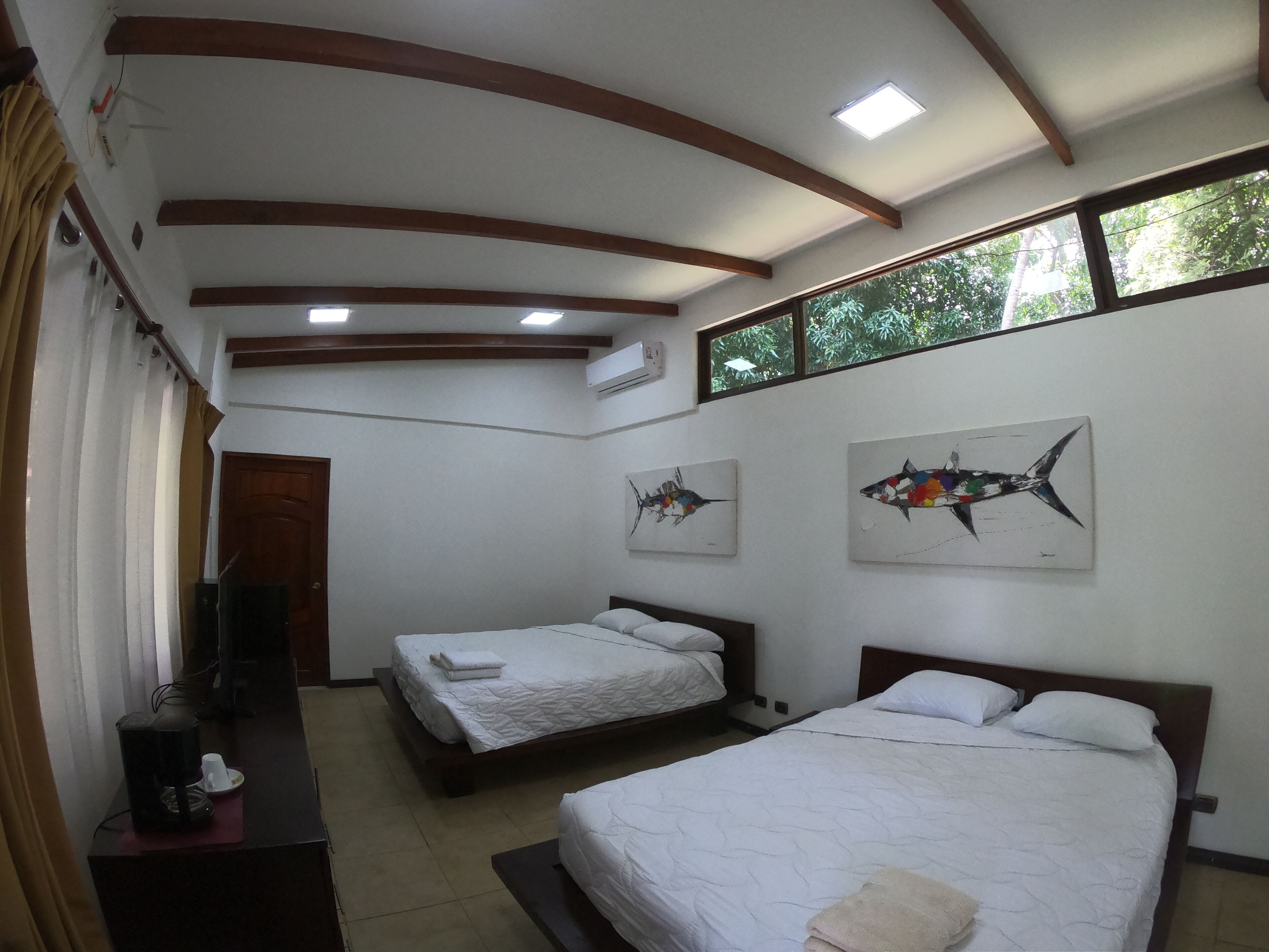 A hotel room with two beds, a coffee maker, and artwork on the walls.