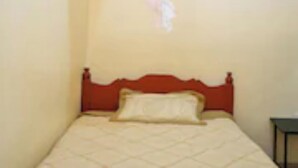 A single bed with a wooden headboard in a room with plain walls.