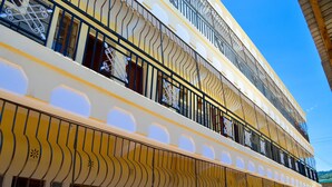 A multi-story building with balconies, large windows, and a yellow and white color scheme.