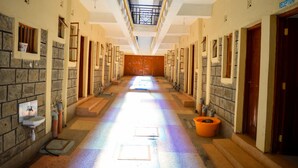 A long, narrow hallway with a reception at the end, stone walls, and a tiled floor.