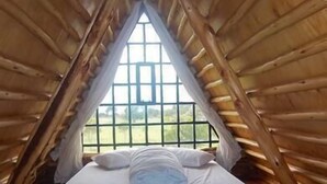 Uma cama de solteiro num quarto com paredes de madeira e janela.