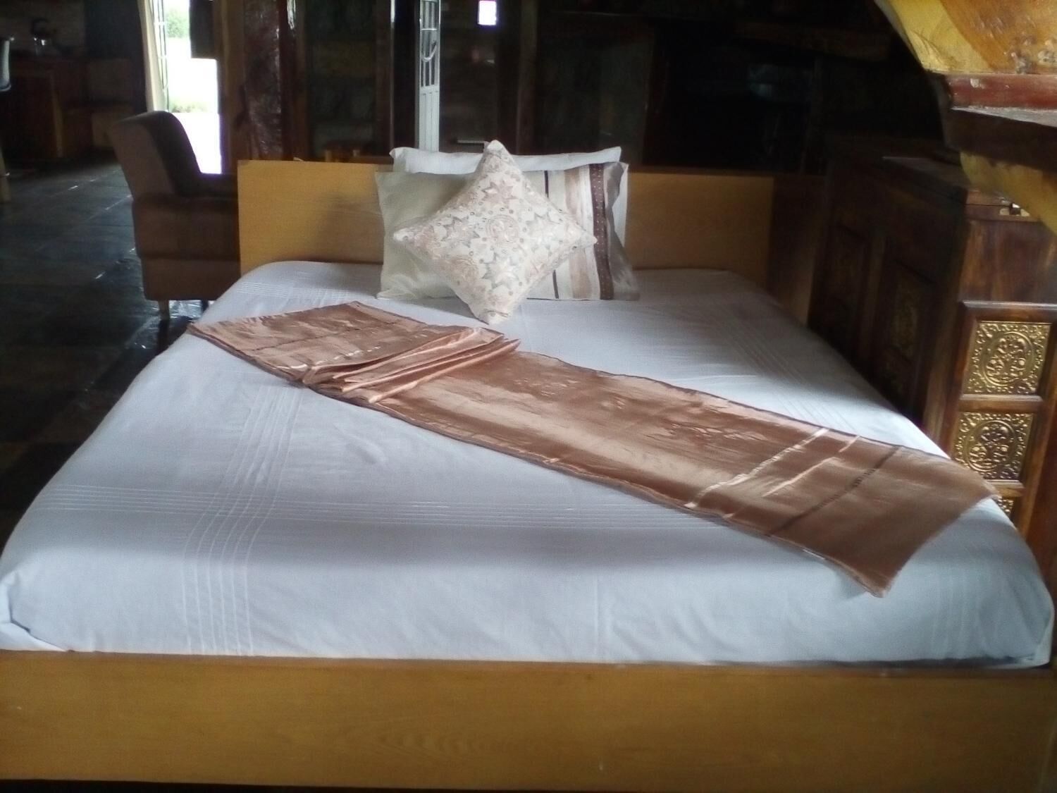 A bed with a white mattress, a brown blanket, and a decorative pillow.