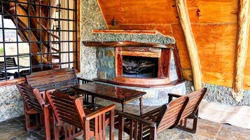 Un interior rústico de madera con chimenea de piedra, muebles de madera y pared de piedra.