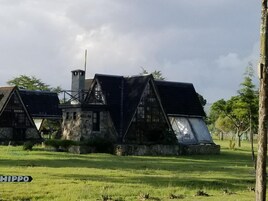 Un edificio rústico de piedra con un techo empinado, ventanas grandes y una chimenea.