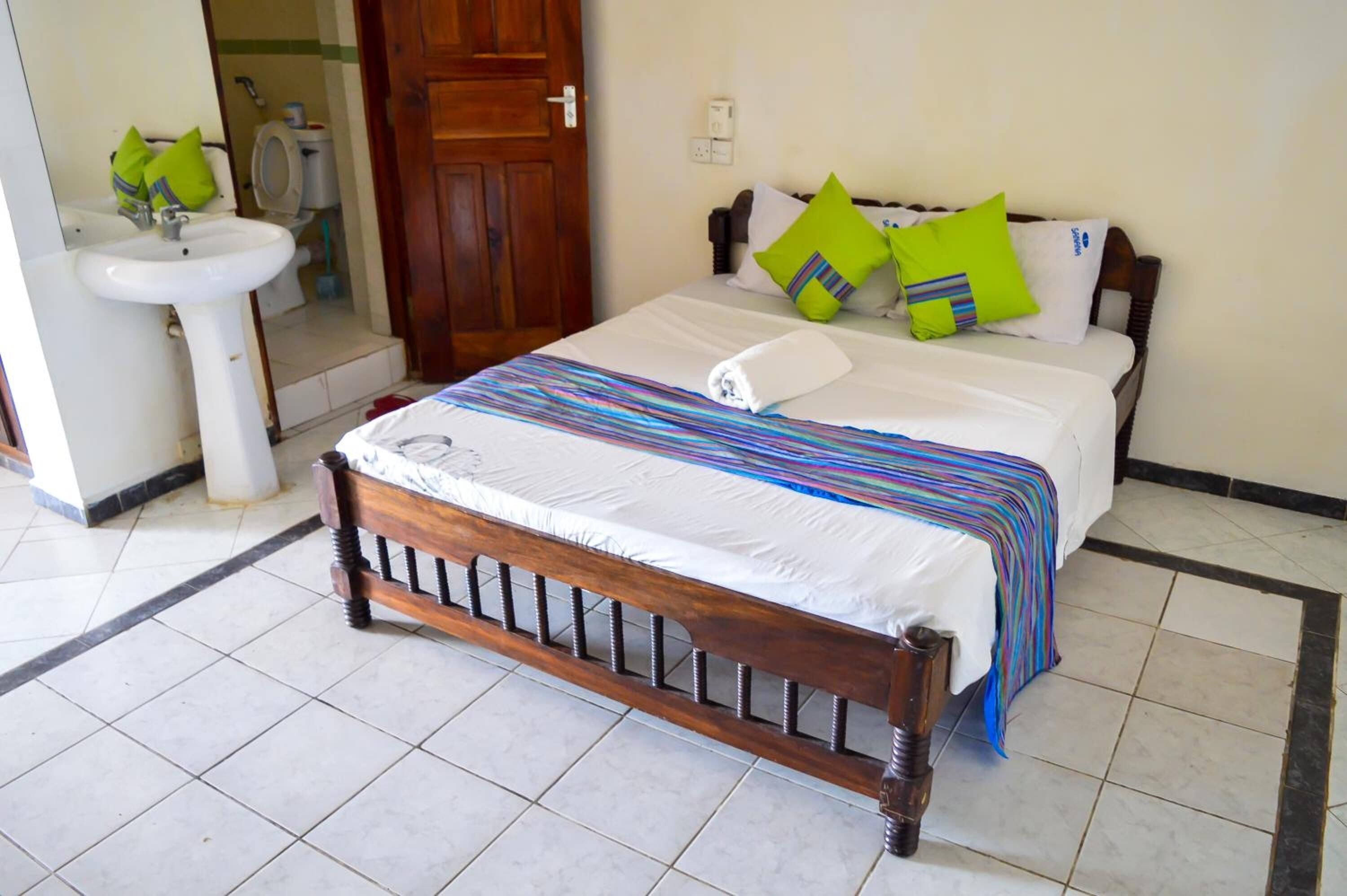 A neatly made bed with a striped blanket, a wooden headboard, and a white pillow.