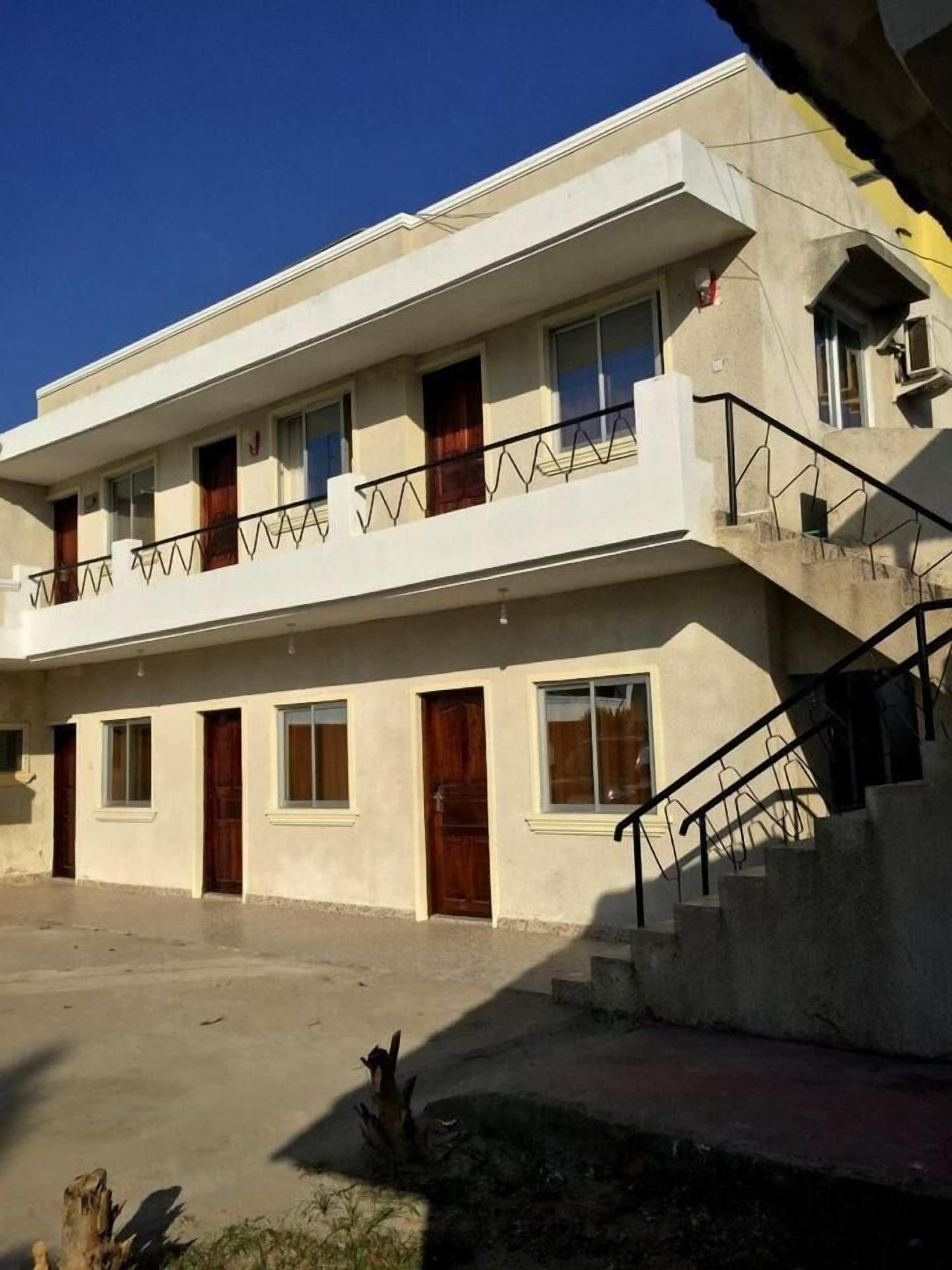 Un edificio de dos pisos con un balcón, una escalera y una entrada plana.