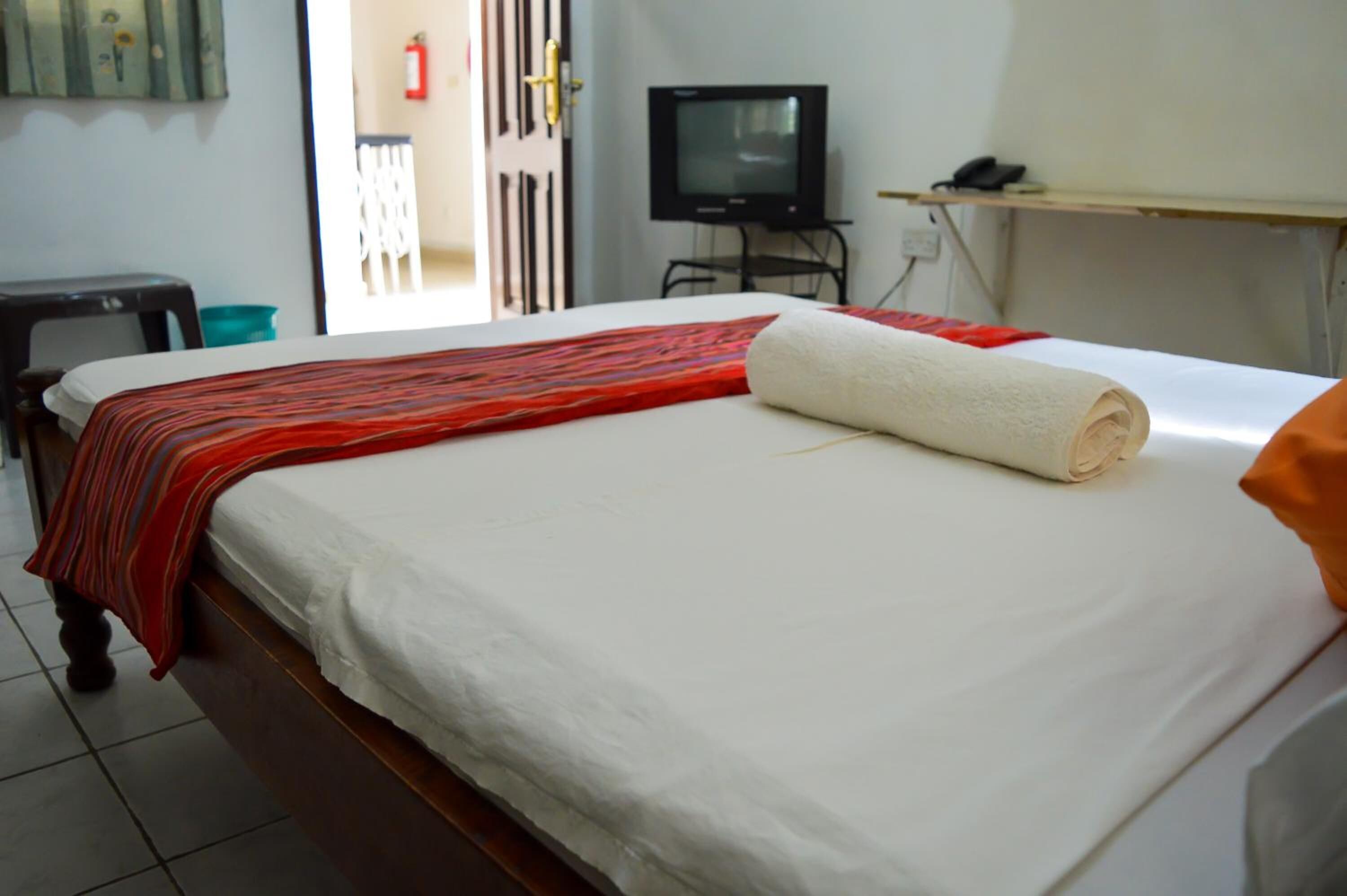 A hotel room with a bed, a television, and a small desk.