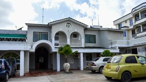 A two-story building with a central entrance, a satellite dish, and a car parked in front. - Sanana Conference Center and Holiday Resort (Mombasa)