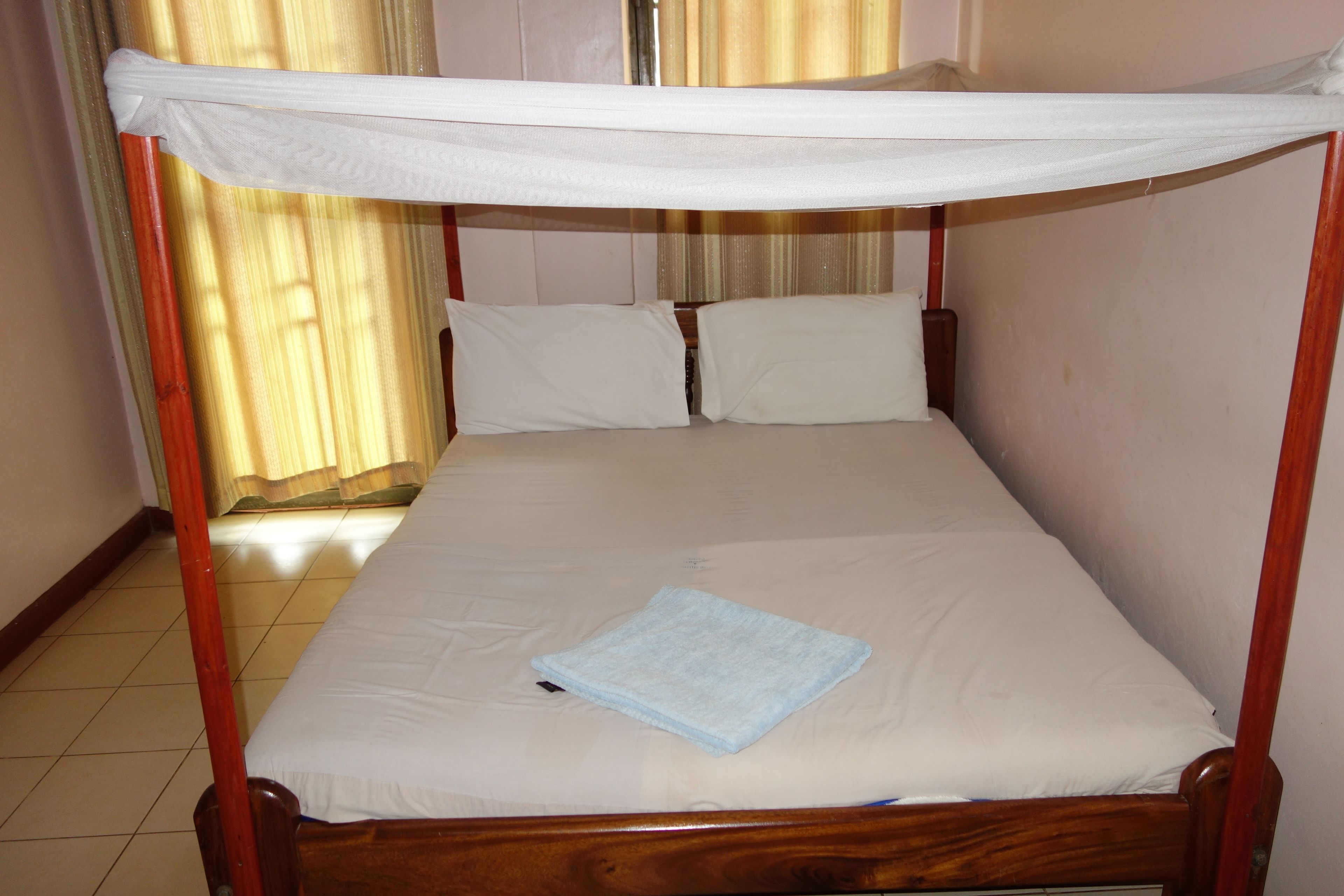 A single bed with a canopy, wooden frame, and white bedding.