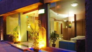 Un moderno vestíbulo de hotel con puertas de vidrio, plantas en macetas y un mostrador de recepción.