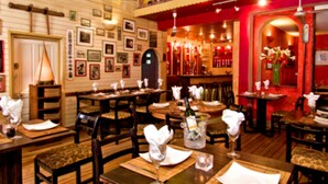 Un interior de restaurante con mesas y sillas de madera, y una pared de acento roja.