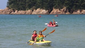 Un grupo de personas haciendo kayak en aguas tranquilas, con una orilla boscosa al fondo.