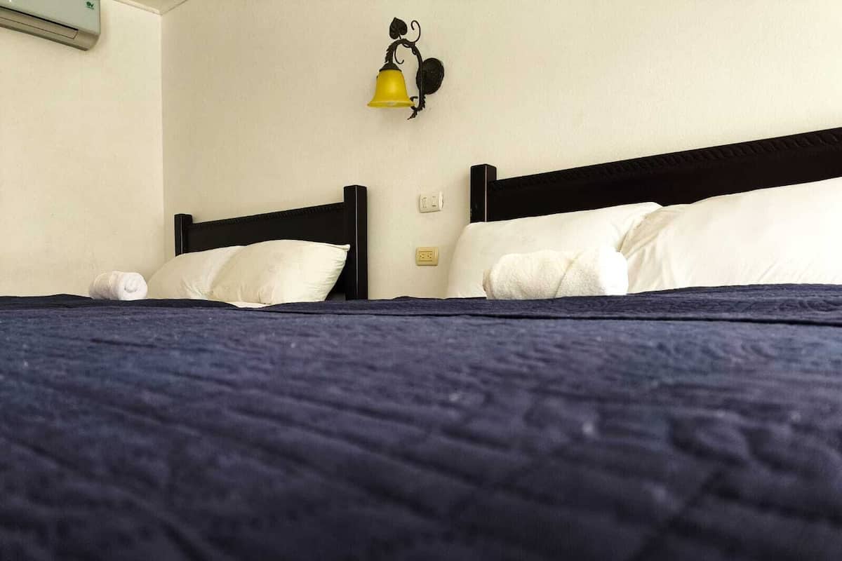 A bed with a dark blue quilt, two white pillows, and a black headboard.