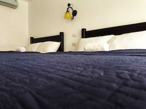 A bed with a dark blue quilt, two white pillows, and a black headboard.