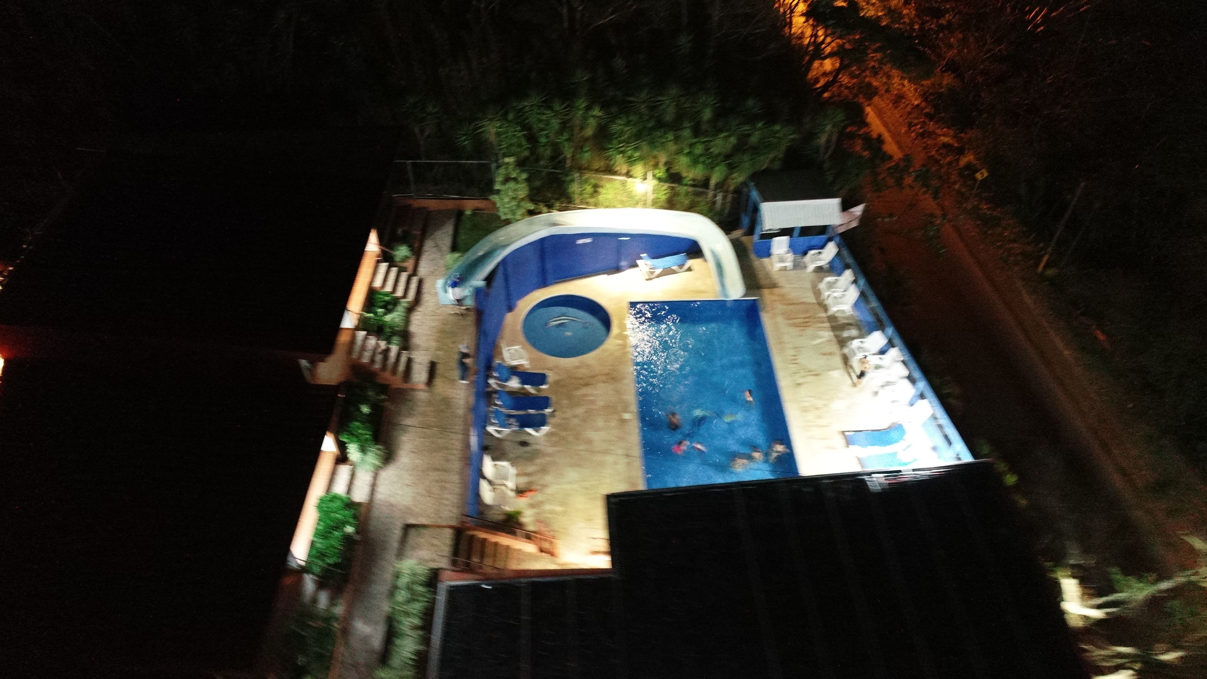 An aerial view of a swimming pool area with a circular hot tub, lounge chairs, and a small deck.