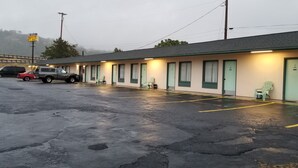 Un motel avec une rangée de chambres, un parking et un panneau indiquant qu’il s’agit d’un commerce de proximité où l’on peut faire un arrêt rapide.