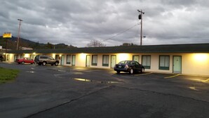 Un motel avec une rangée de chambres, un parking et un panneau indicateur en arrière-plan.