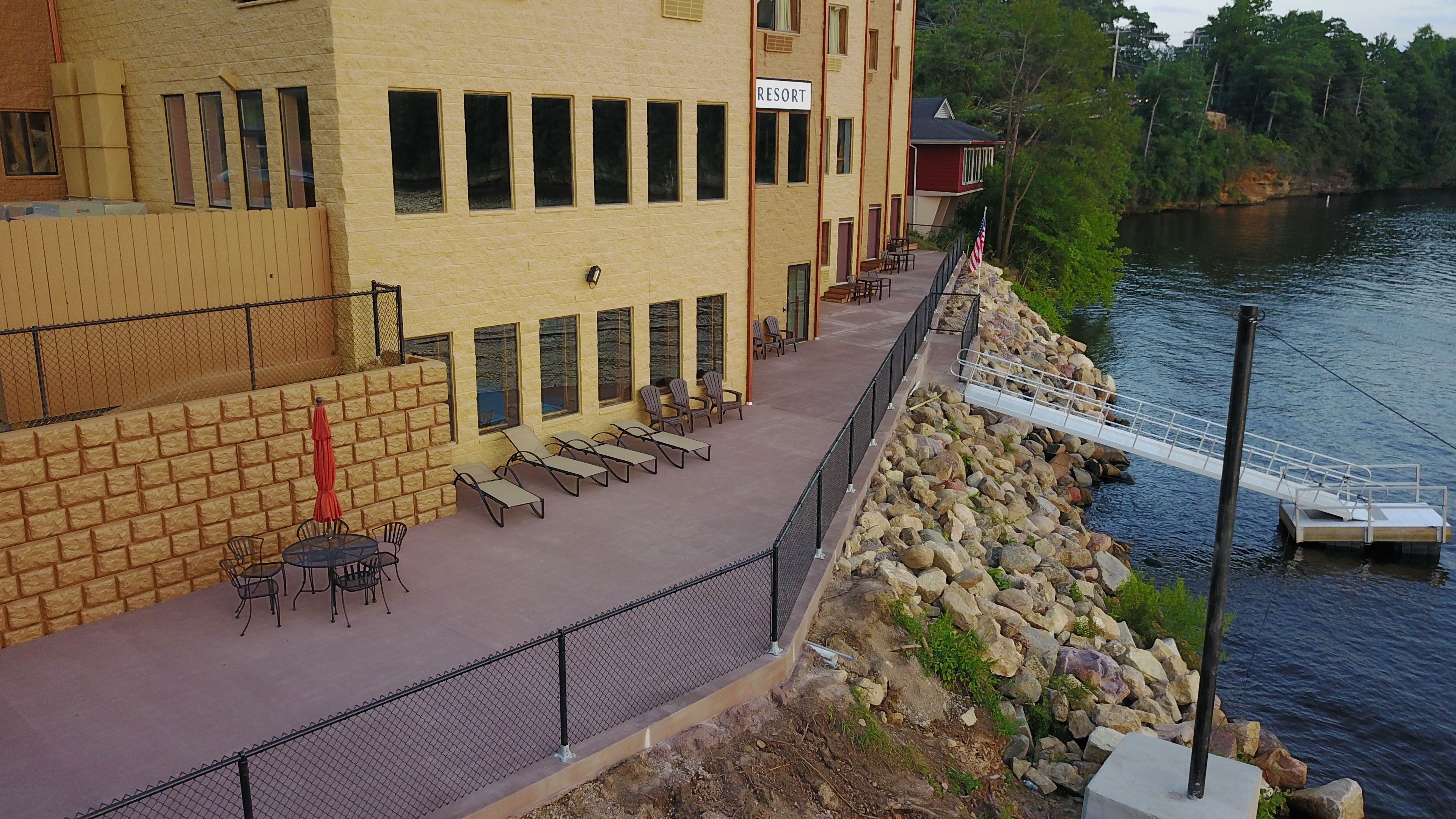 A resort building with a pool area, outdoor seating, and a view of the water.