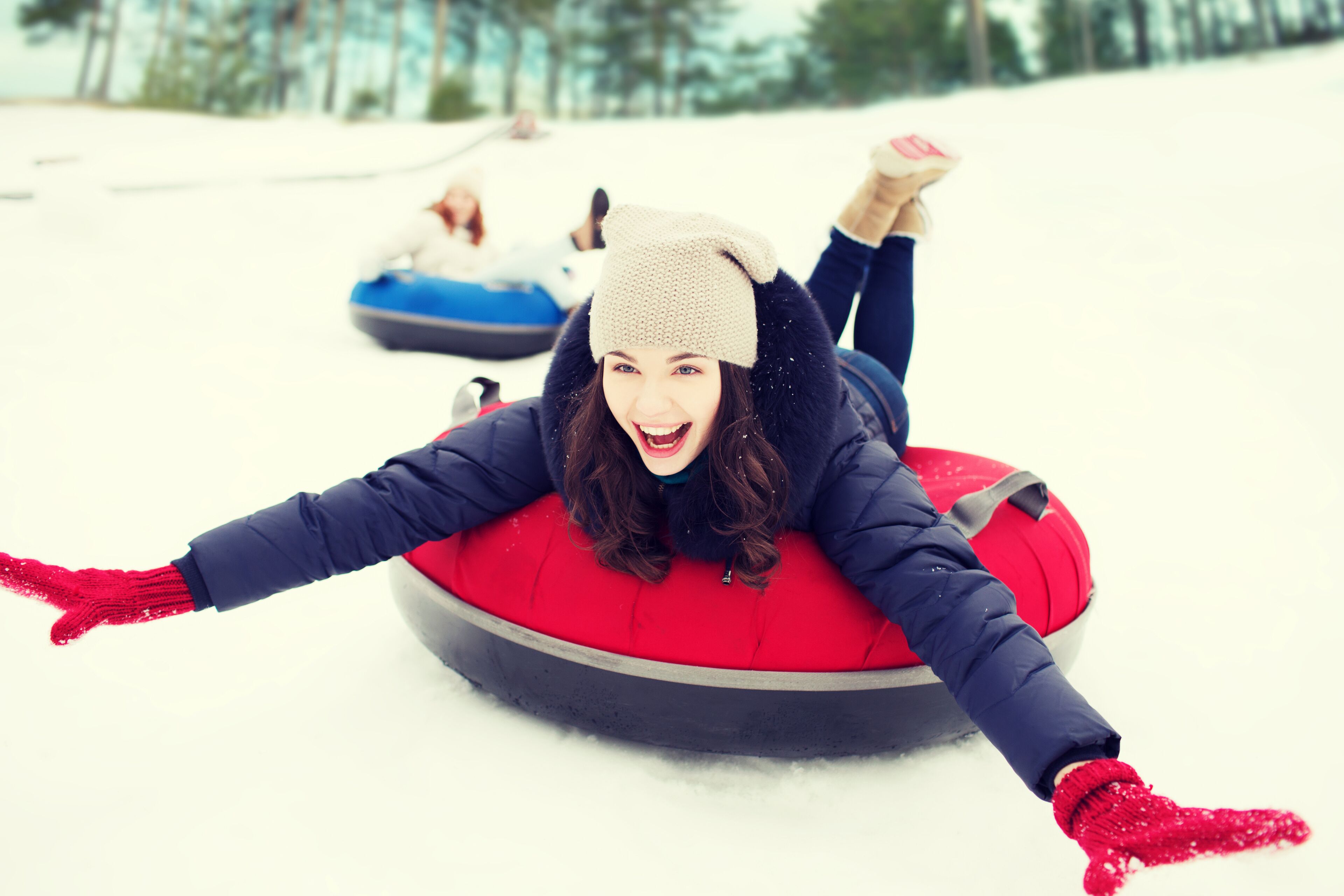 A person lying on a snow tube in a snowy area.