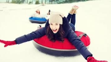 A person lying on a snow tube in a snowy area.