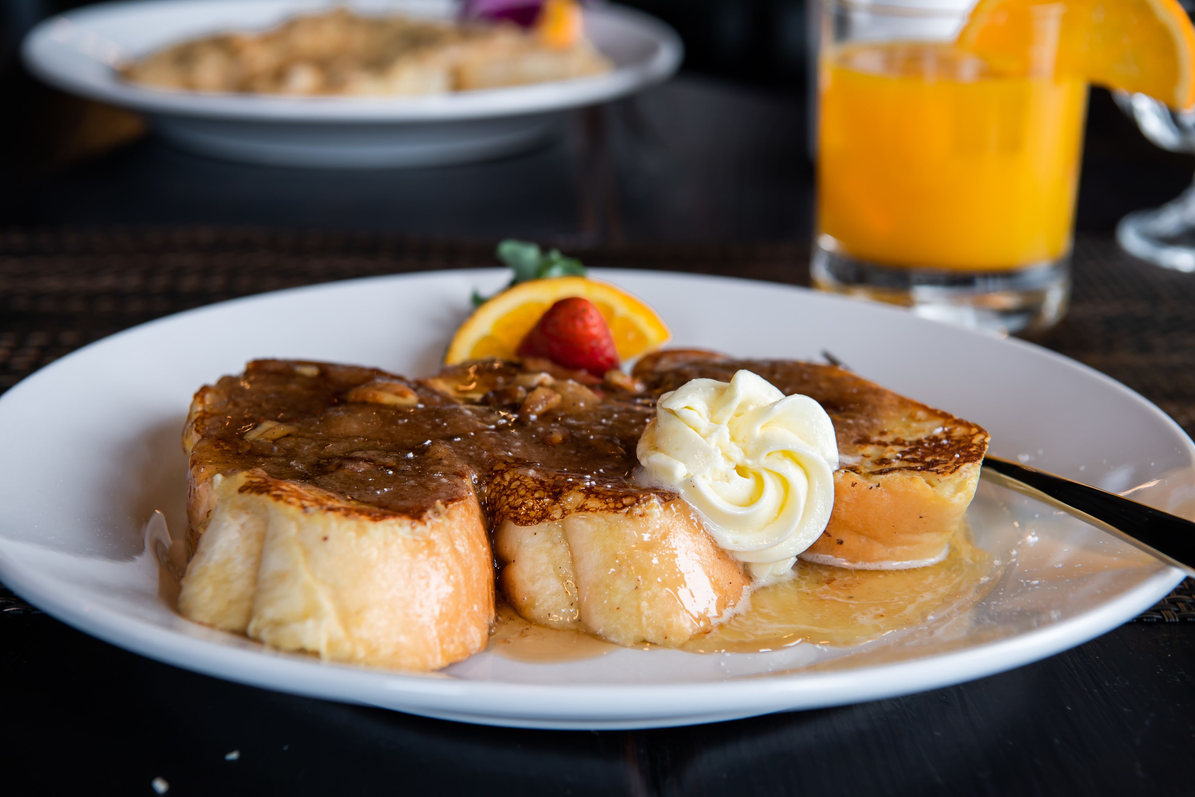 A plate with a grilled item, possibly steak, accompanied by a dollop of sauce and a slice of orange.