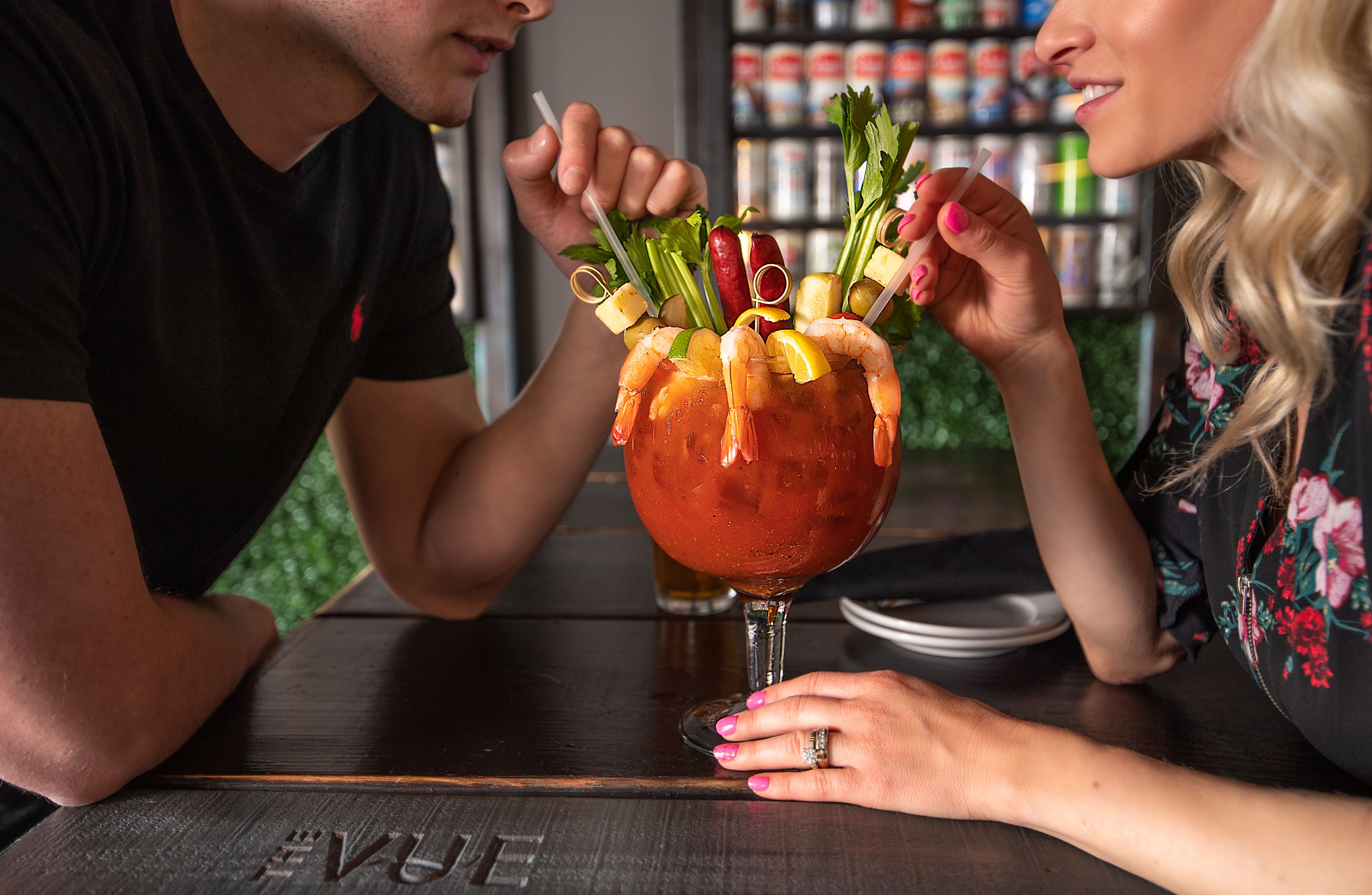 Une personne tenant un cocktail décoré de divers fruits et légumes.