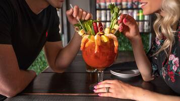 Une personne tenant un cocktail décoré de divers fruits et légumes.