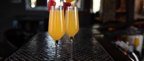 Two glasses of orange juice on a metal bar counter with a hexagonal pattern.
