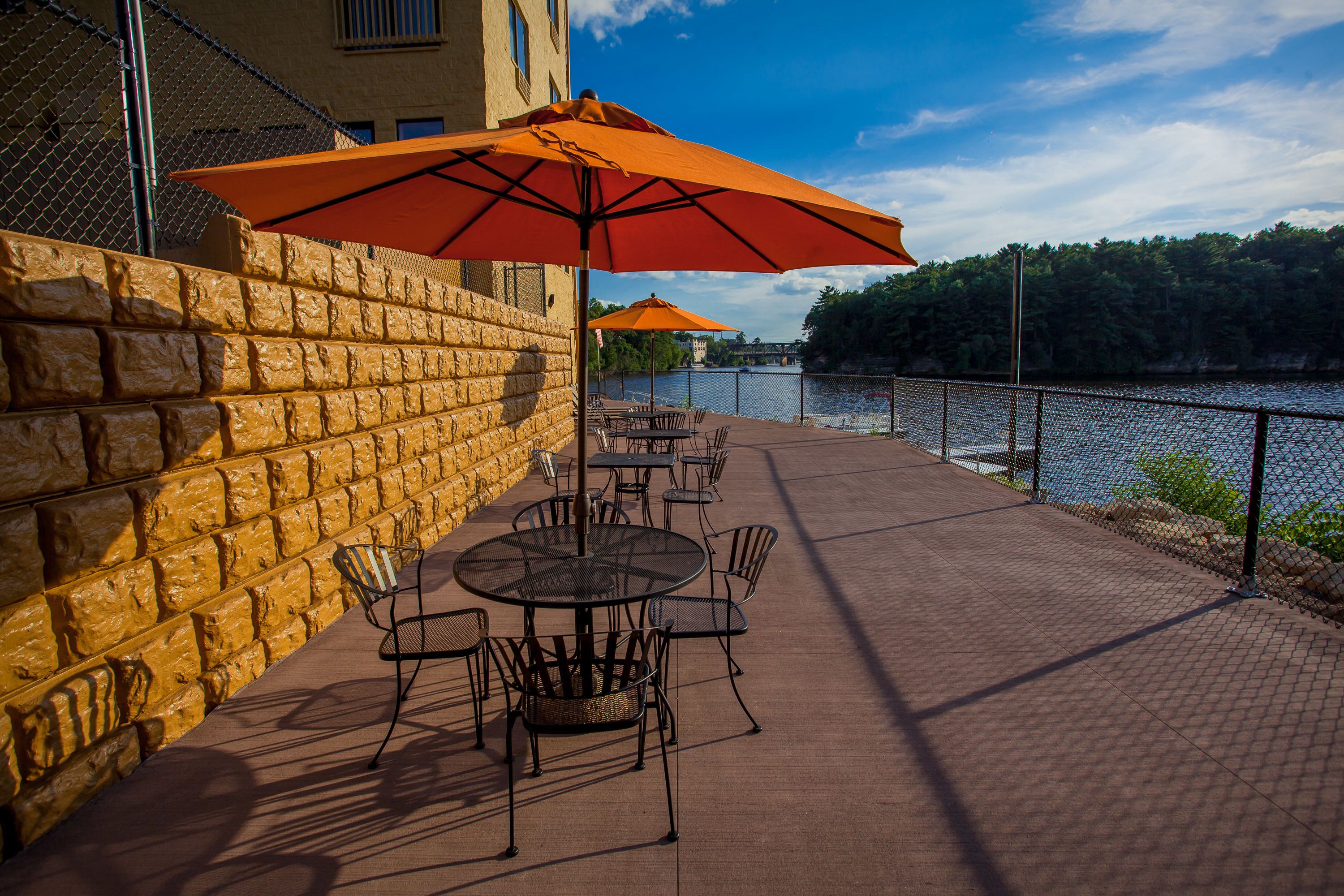 Eine Terrasse mit Sitzgelegenheiten, eine Steinsäule und ein Blick auf einen Fluss.
