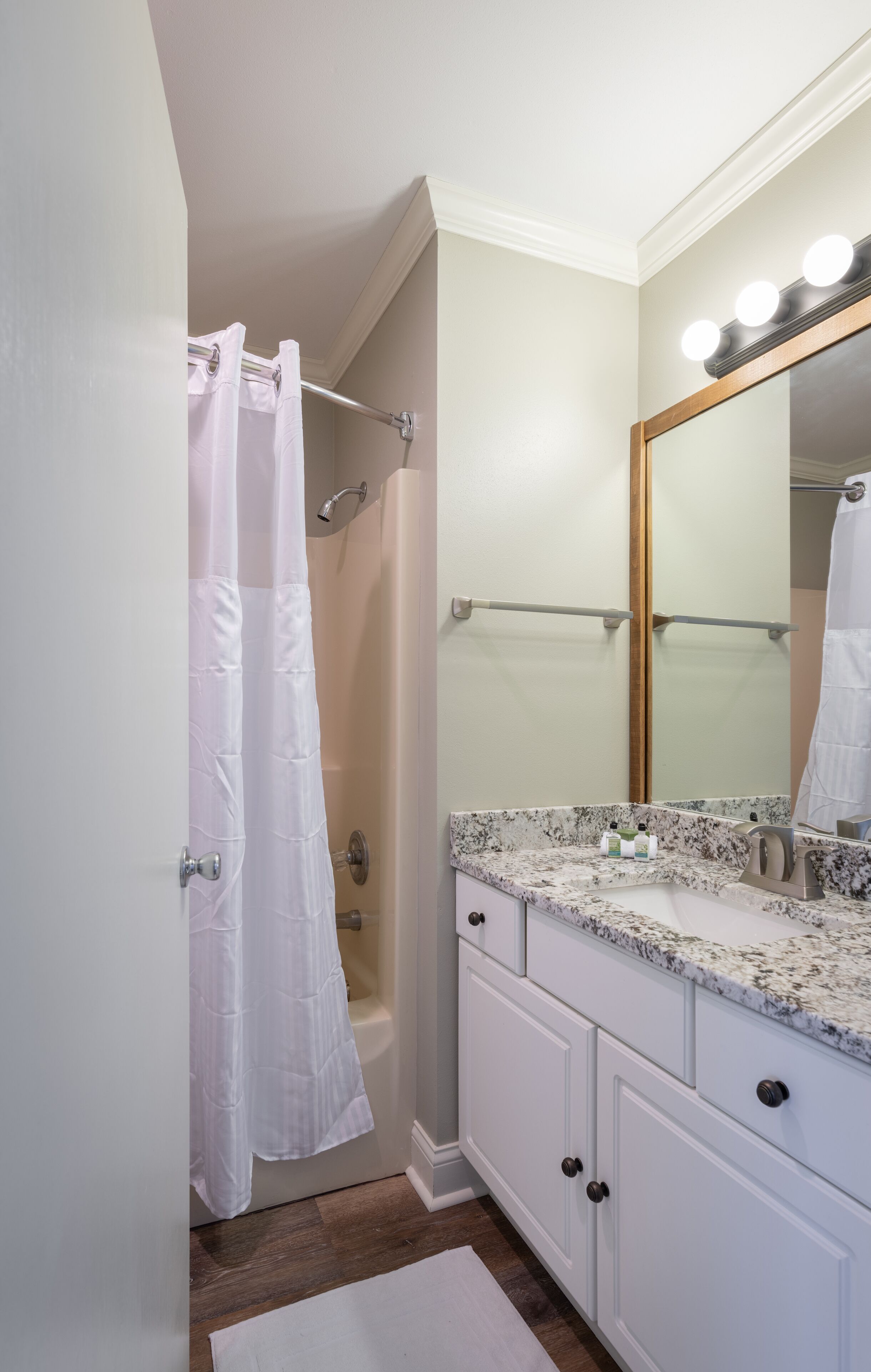 A bathroom with a shower, a vanity with a mirror, and a towel rack.