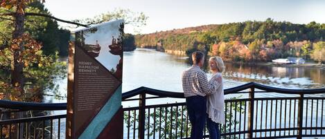 A couple standing by a lake with a historical marker in the foreground.