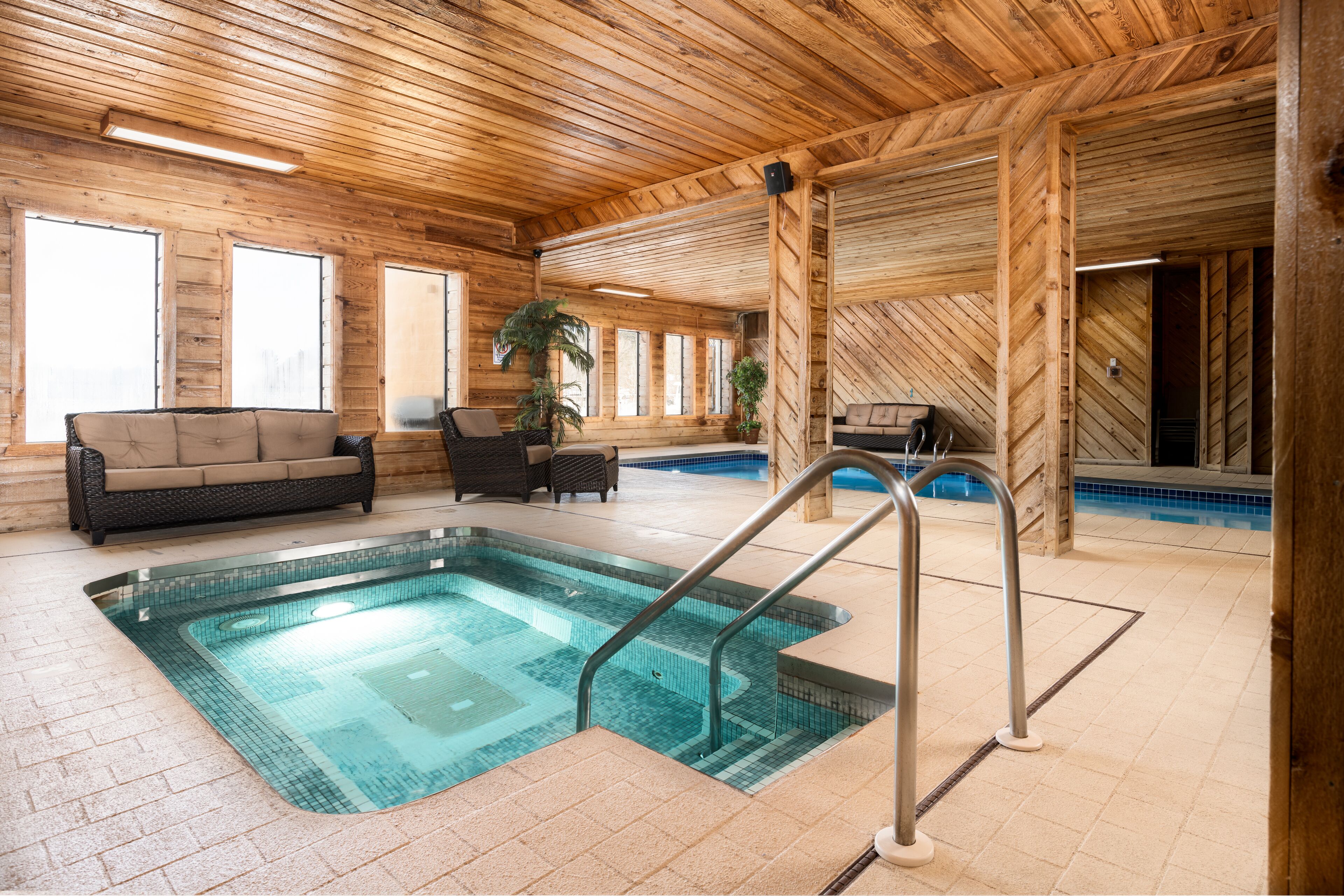 An indoor swimming pool with a wooden interior, a sofa, and a chair.