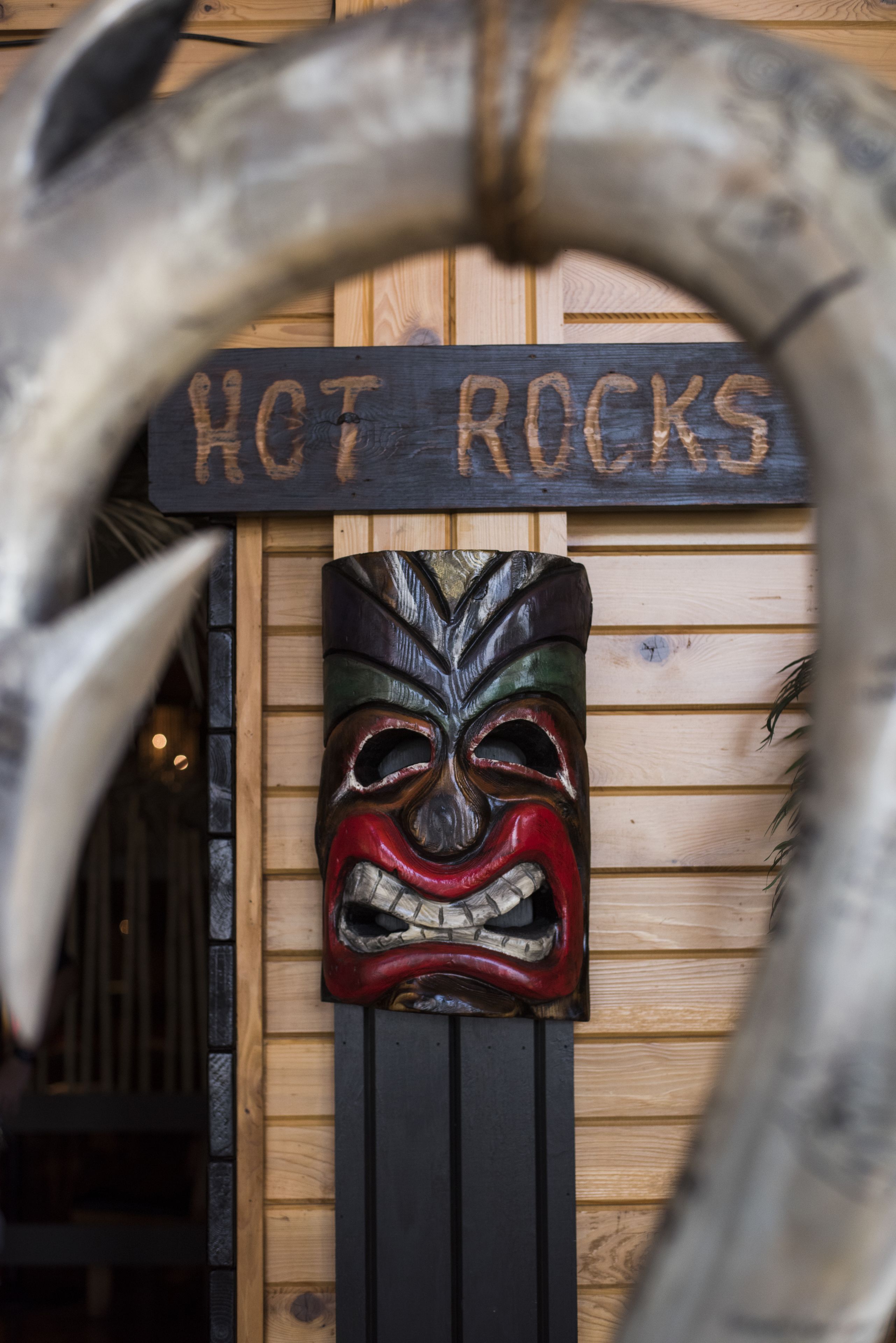 A wooden wall with a sign that reads "HOT ROCKS" and a carved wooden mask.