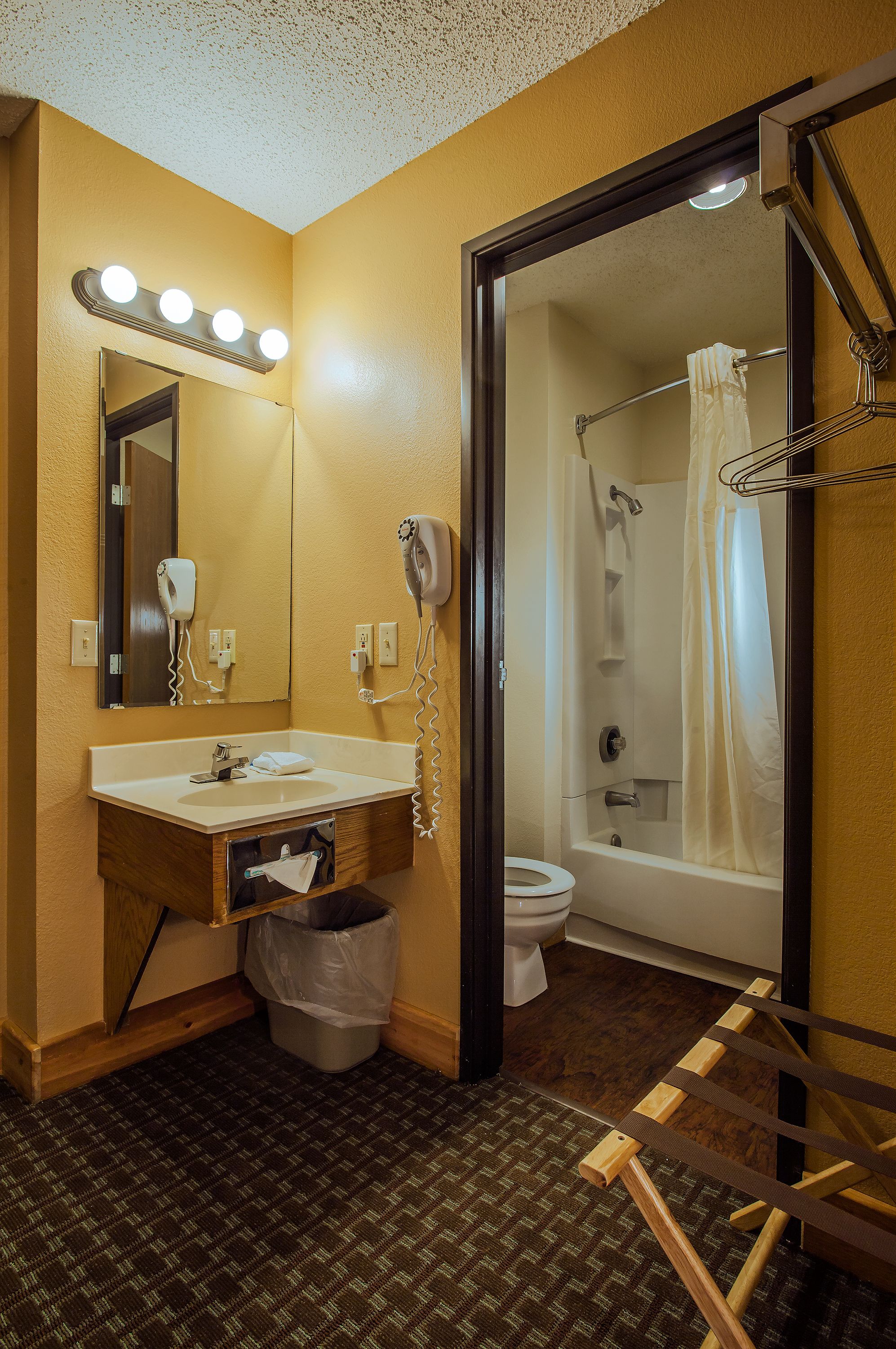 Een badkamer met een wastafel, spiegel, haardroger en douche.