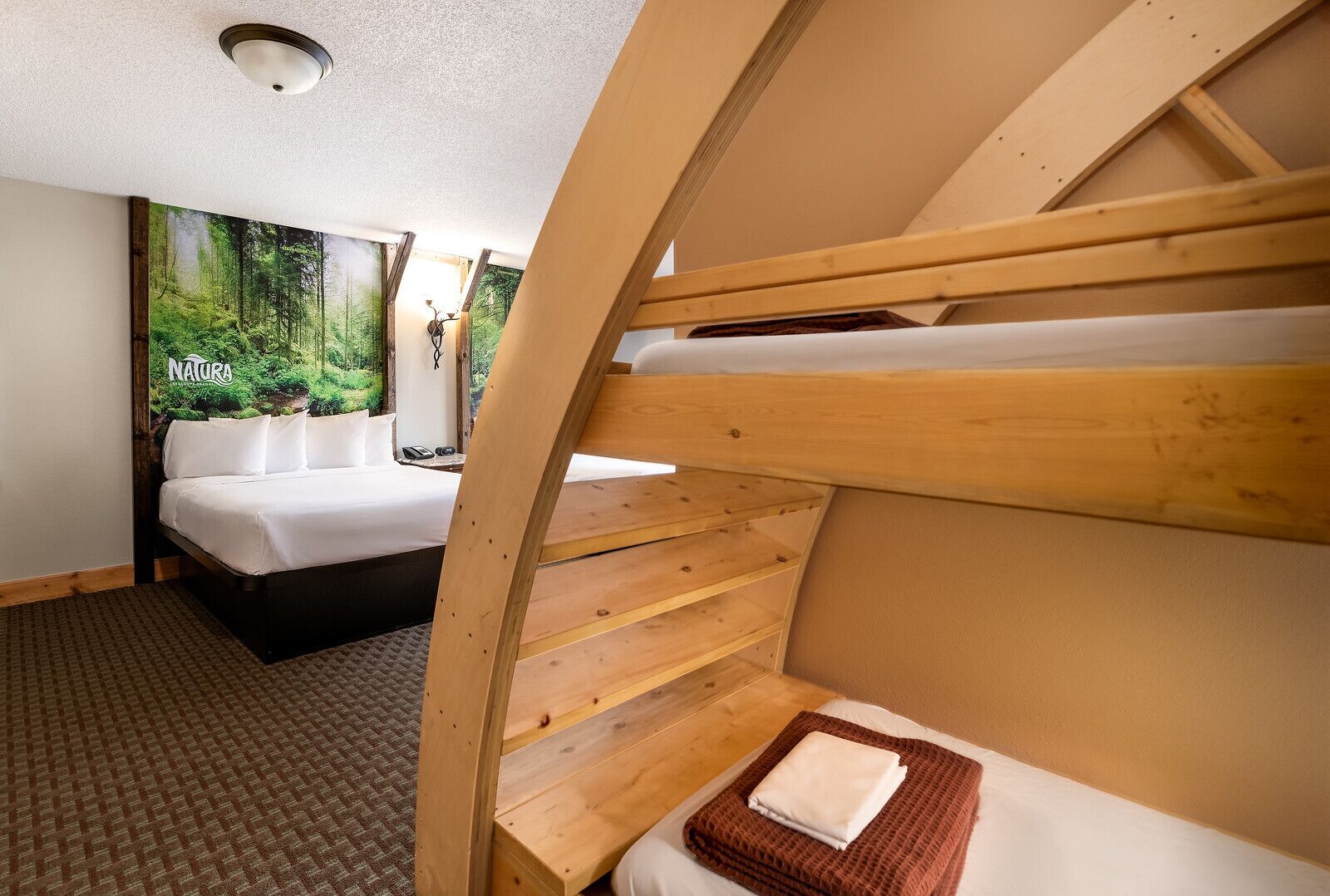 A room with a bunk bed, a single bed, and a large poster of a forest.
