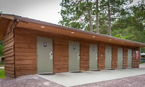 A row of log-style restrooms with individual doors, each marked with a restroom sign.