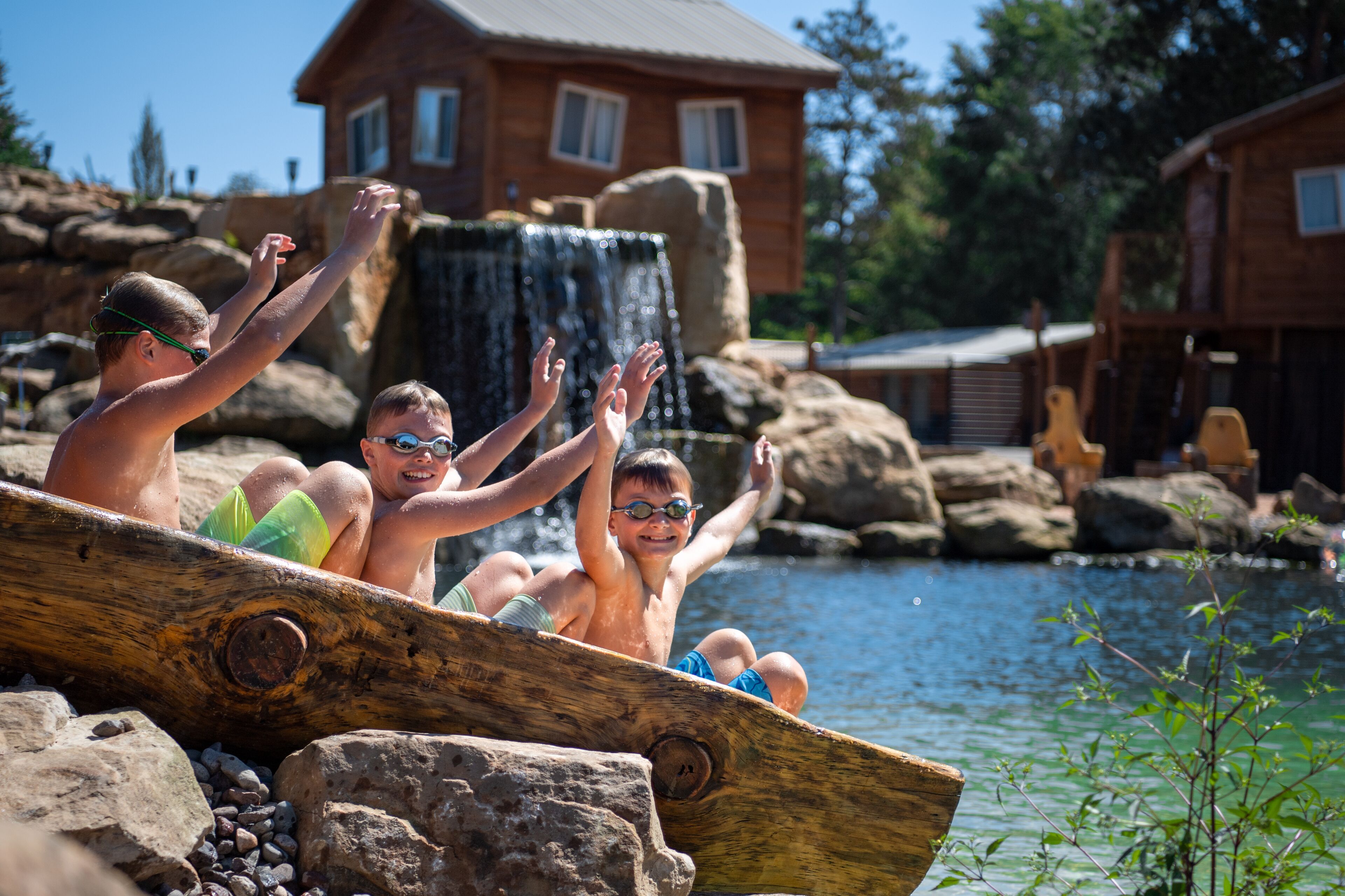 A wooden boat with people enjoying a waterfall view.