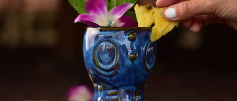 A hand placing a slice of watermelon into a decorative blue vase with a floral design.