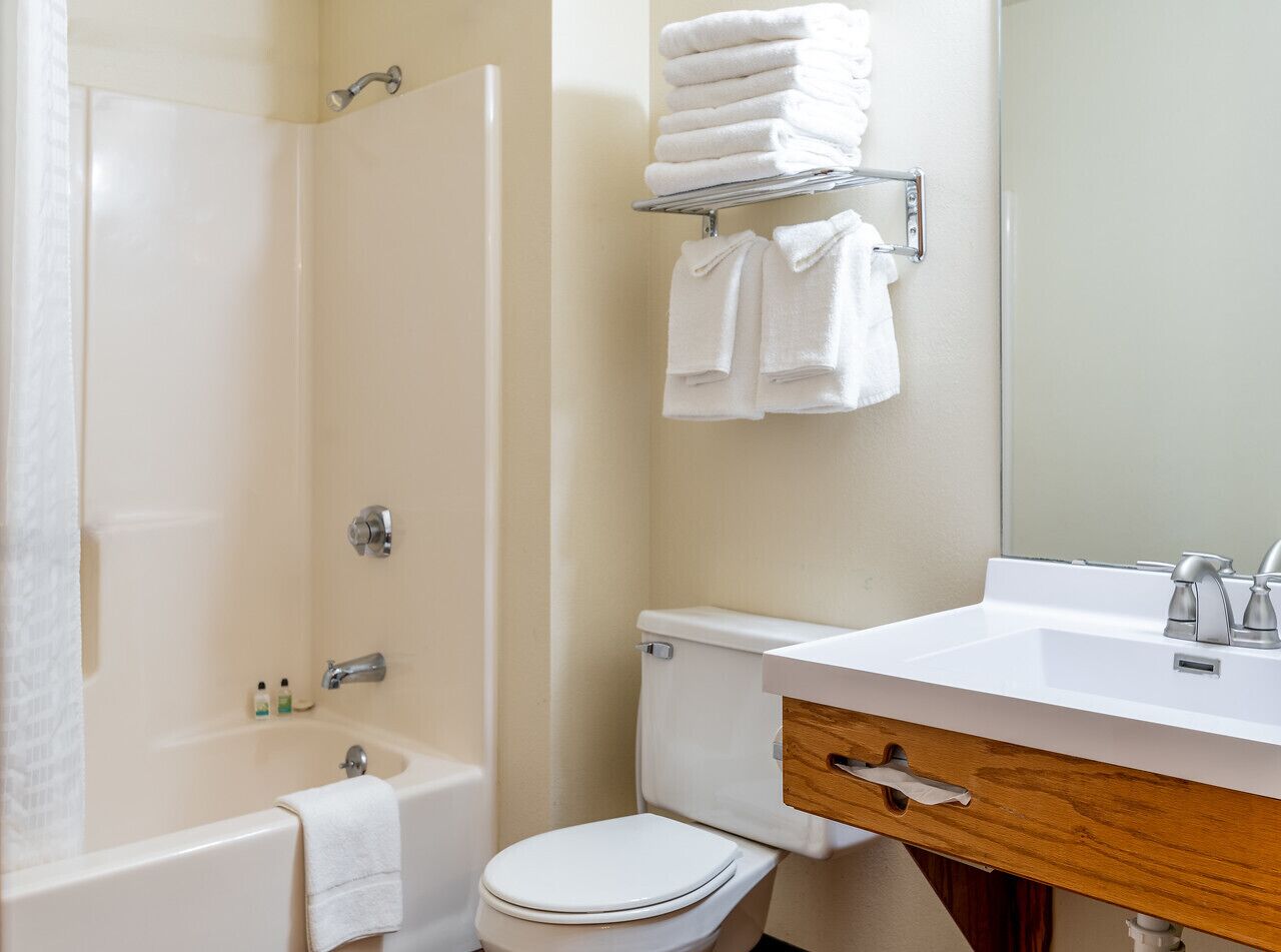 A bathroom with a bathtub, toilet, sink, and a towel rack with folded towels.