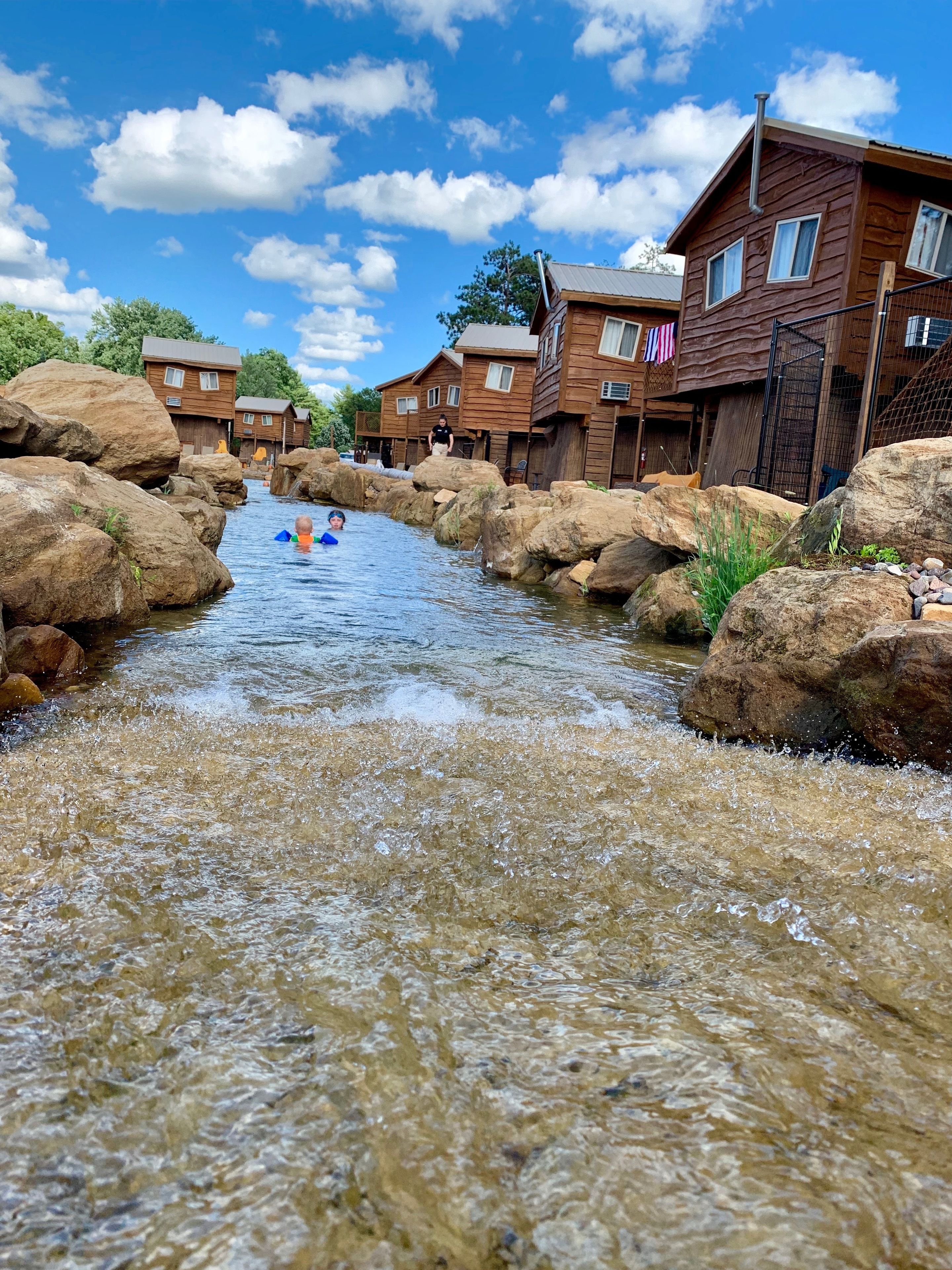 A river flowing through a rustic area with wooden houses and large rocks.