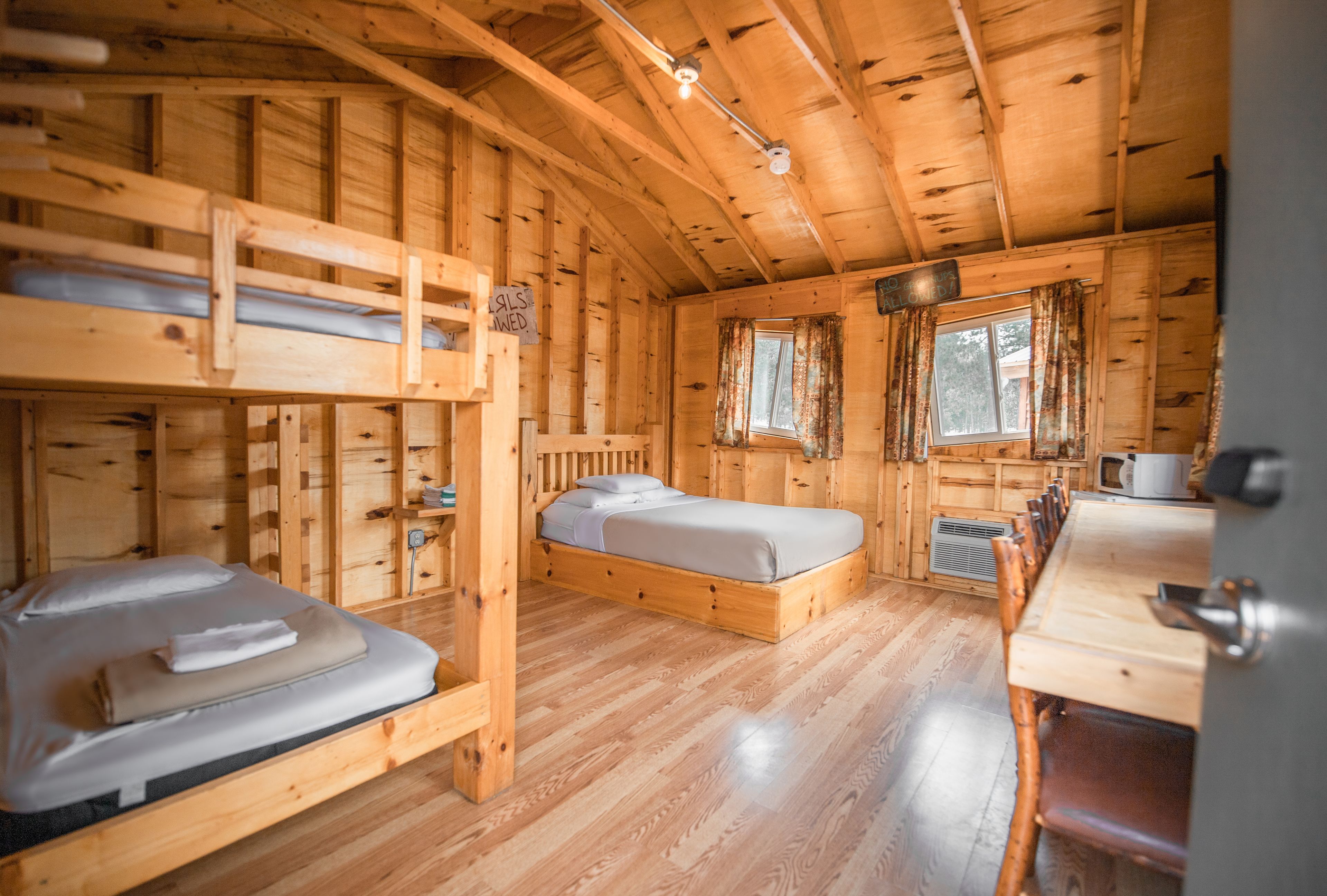 A cabin interior with bunk beds, a dining table, and a kitchen area.