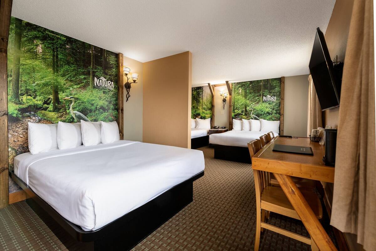 A hotel room with a large bed, a smaller bed, a desk, and a television.