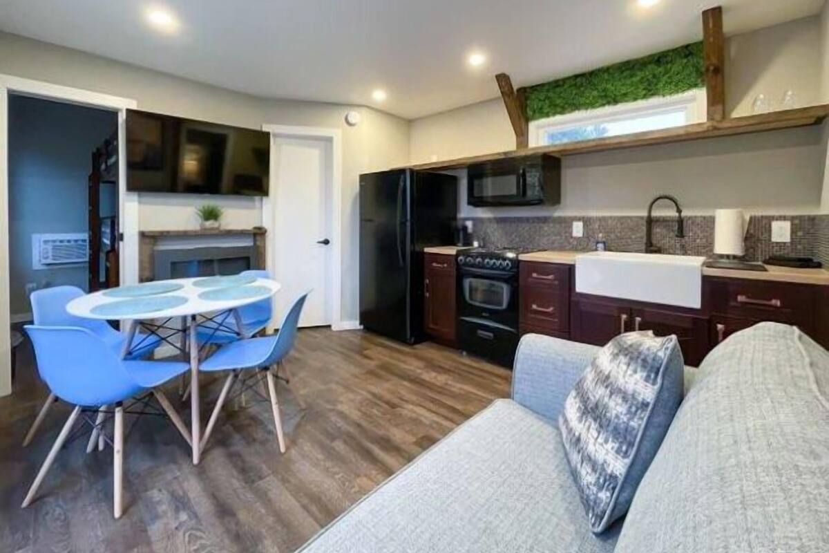 A compact kitchen with modern appliances, a dining area with a round table and chairs, and a cozy seating area with a sofa.