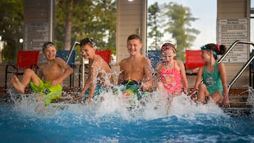 A group of people in a swimming pool with water splashing around them.