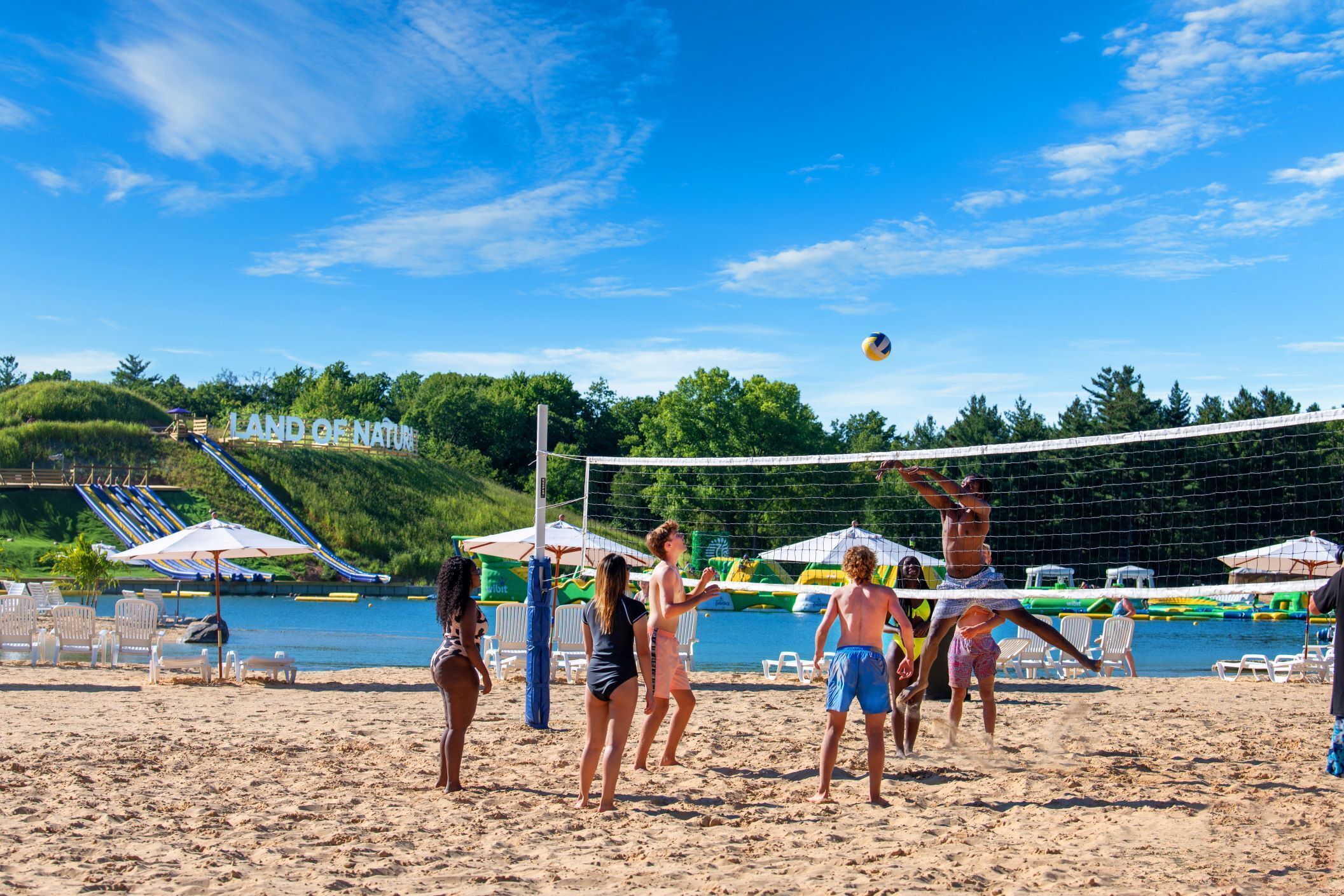 A beach volleyball game with players and spectators.