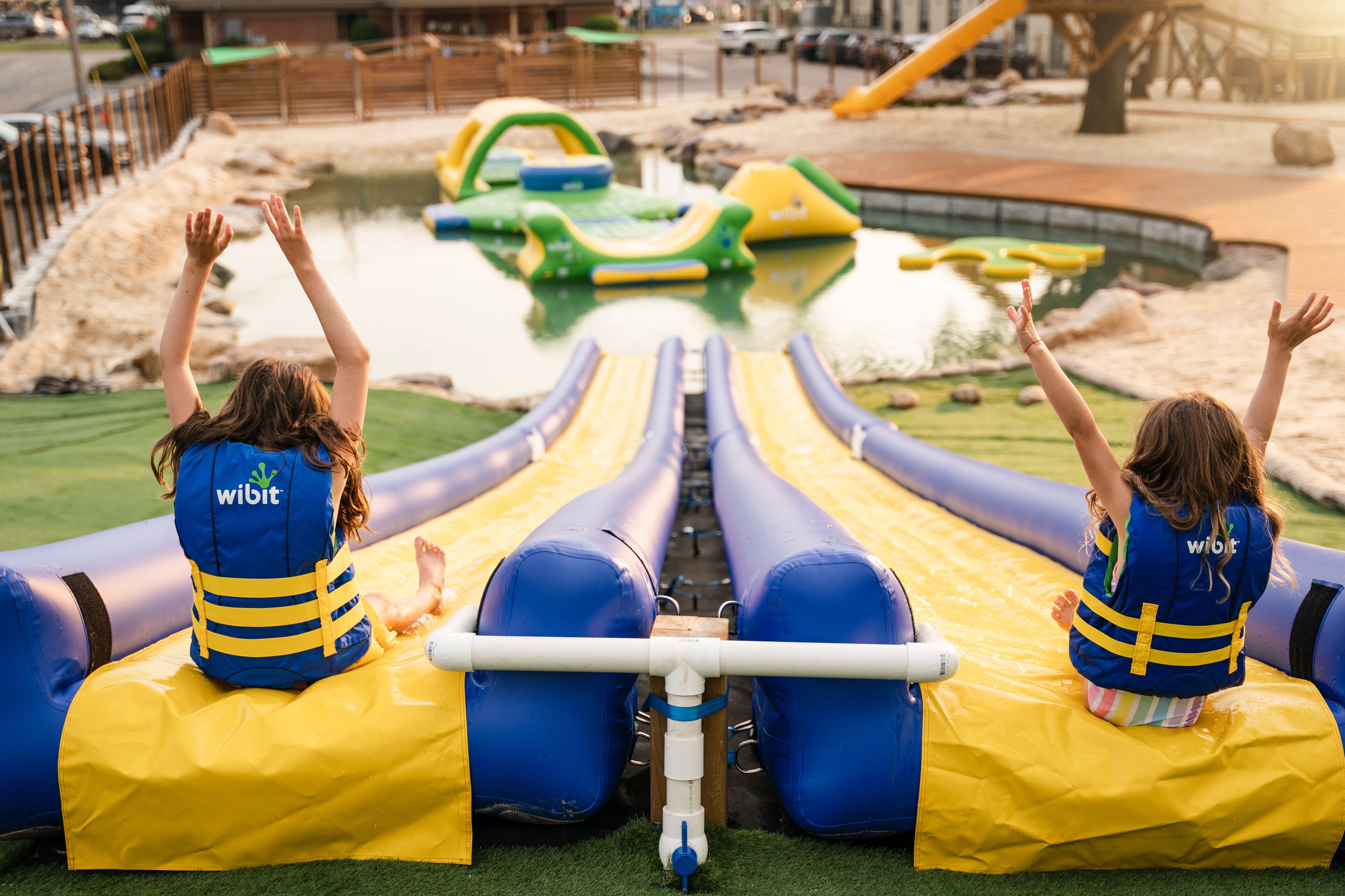 Two children on inflatable slides at a water park.
