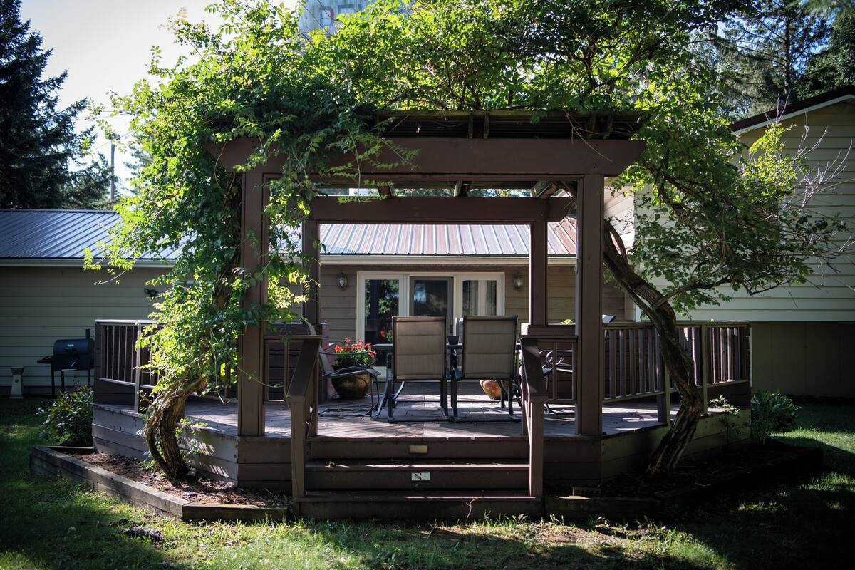 A covered outdoor seating area with a pergola, chairs, and a table.